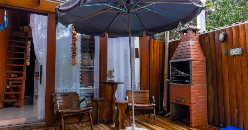 a patio with an umbrella and chairs and a fireplace at Pousada e Chalé Lote 22 in Ilha do Mel