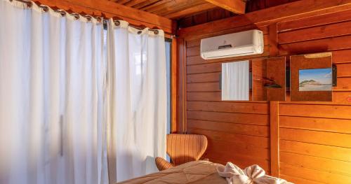 a bedroom with a bed and a window with a curtain at Pousada e Chalé Lote 22 in Ilha do Mel
