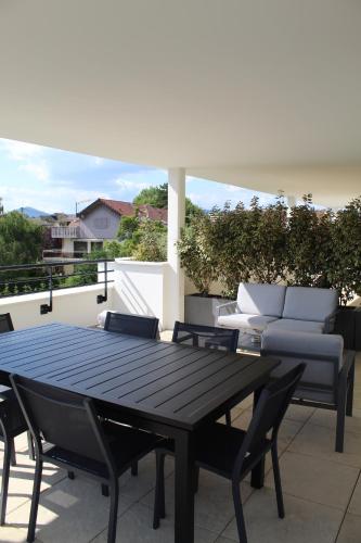 une table noire et des chaises sur une terrasse dans l'établissement Hôtel Les Muses, à Annecy