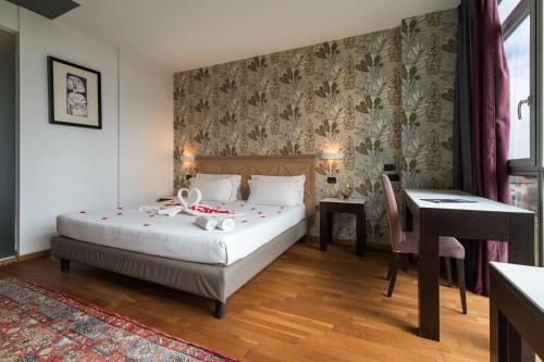 a bedroom with a bed and a table and a desk at Hotel Antares Sport Beauty & Wellness in Villafranca di Verona