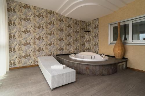 a bathroom with a tub and a table with a bench at Hotel Antares Sport Beauty & Wellness in Villafranca di Verona