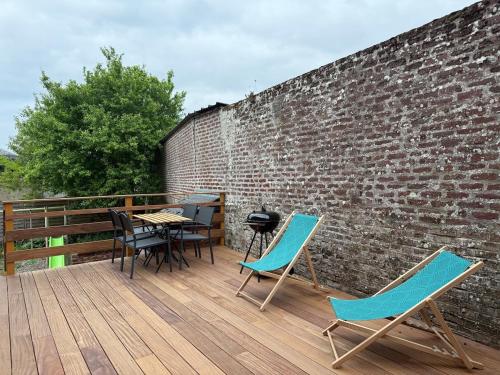 a patio with chairs and a grill on a brick wall at maison de charme au coeur de la baie de somme in Noyelles-sur-Mer
