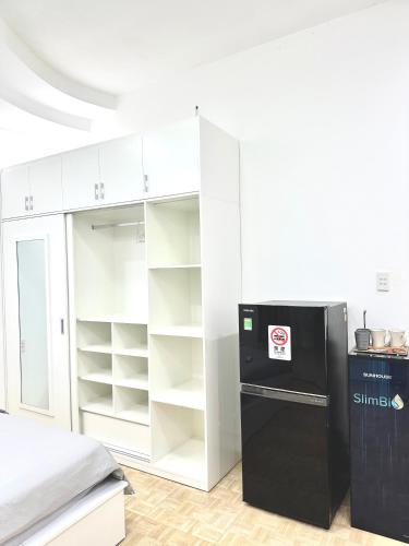 a kitchen with a black refrigerator and white cabinets at Nemaru urban stay in Ho Chi Minh City