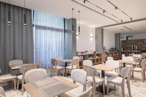 a restaurant with tables and chairs and a kitchen at Boe Luxury Hotel in Sarandë