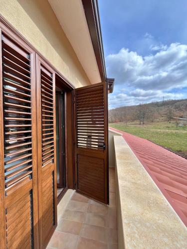 a balcony with wooden doors and a view of a field at Alberi Maestri Eco Retreat in Satriano di Lucania