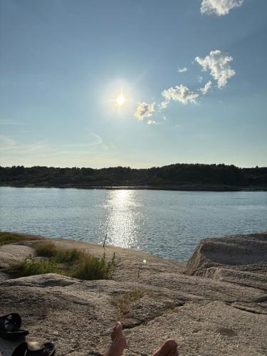 a person sitting on a rock near a body of water at Strand 18b in Grebbestad