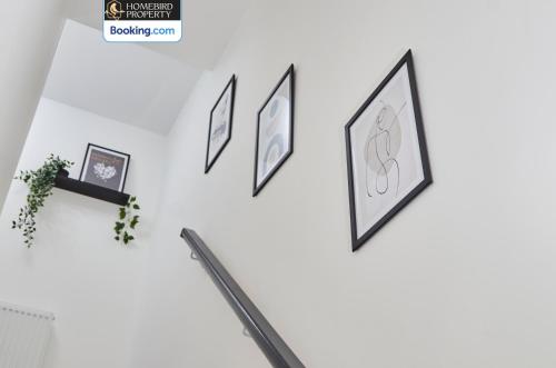 a wall of framed pictures on a white wall at Luxurious 4Bedroom House By Homebird Property Management Short Lets & Serviced Accommodation Leeds With Private Parking, Garden & Patio Area in Leeds