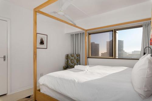 a bedroom with a white bed and a large mirror at Central Sea Point Aprt Pool Promenade in Cape Town