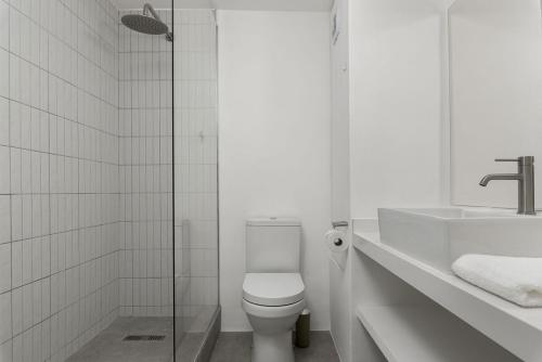 a white bathroom with a toilet and a sink at Central Sea Point Aprt Pool Promenade in Cape Town
