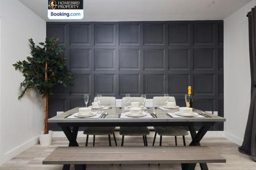 a dining room table with chairs and a black wall at Luxurious 4Bedroom House By Homebird Property Management Short Lets & Serviced Accommodation Leeds With Private Parking, Garden & Patio Area in Leeds