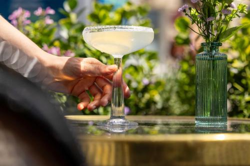 a person holding a martini glass next to a vase at Hotel Observatoire Luxembourg in Paris