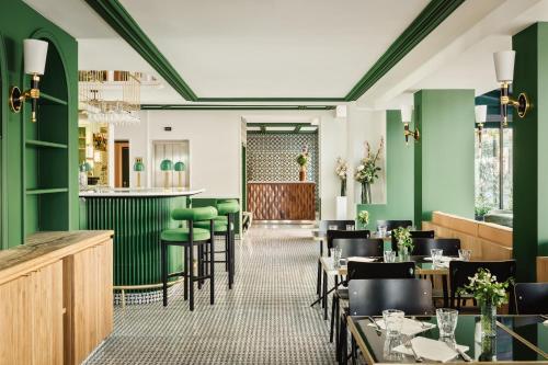 a restaurant with green walls and tables and chairs at Hotel Observatoire Luxembourg in Paris