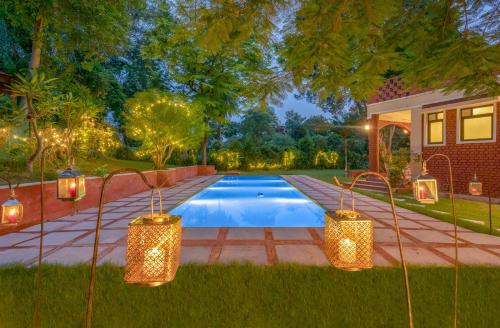 a swimming pool in a yard with lights next to a house at Hostie Tranquil Greens farmhouse near Golf course road Gurgaon in Gurgaon