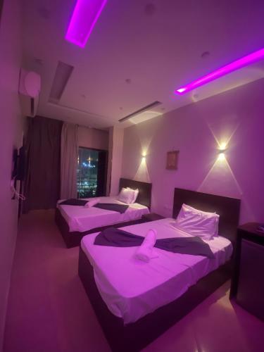 two beds in a room with purple lighting at secret of pyramids view in Cairo