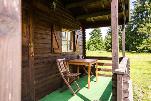 a wooden table and chair on the porch of a cabin at Chatky na Borovej Sihoti - spoločné wc a sprchy in Podtureň