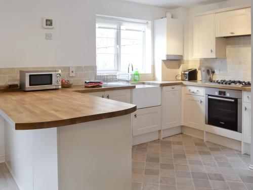 a kitchen with white cabinets and a wooden counter top at Woodland View in Shanklin
