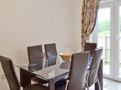 a dining room with a glass table and chairs at Woodland View in Shanklin