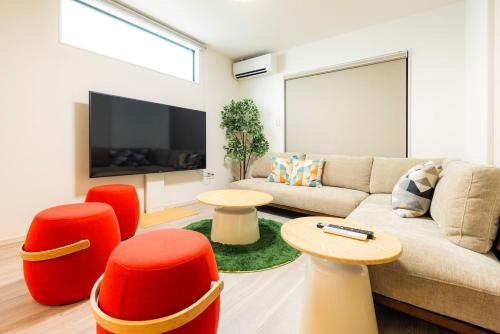 a living room with a couch and chairs and a tv at Amp Flat Dazaifu Ishizaka in Dazaifu