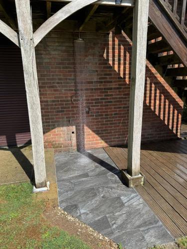 a building with a brick wall and a wooden deck at The Annexe @ Mandalay Lodge in Medstead