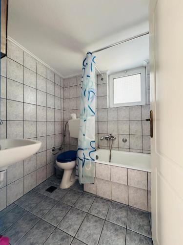 a bathroom with a toilet and a tub and a sink at Maria's apartment in Térsa