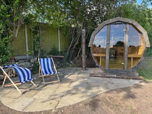a couple of chairs sitting in front of a round mirror at The Annexe @ Mandalay Lodge in Medstead