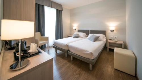 a hotel room with a bed and a desk with a lamp at Hotel Eden Garda in Garda