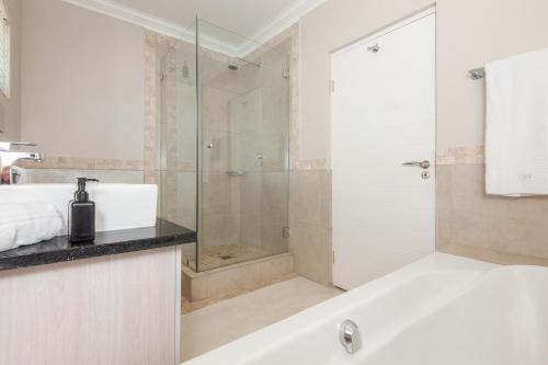 a bathroom with a shower and a tub and a sink at Spatalla Holiday Homes in Kleinmond