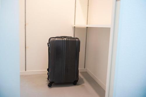 a black suitcase is standing in a hallway at kotinoma kuu in Hakozaki