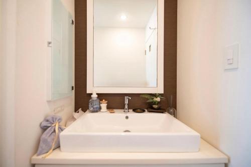 a white sink in a bathroom with a mirror at kotinoma kuu in Hakozaki