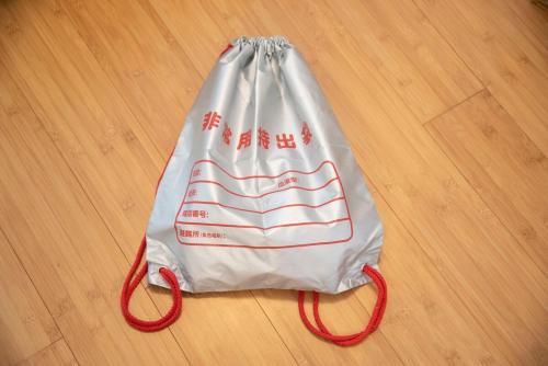 a white bag with red handles on a wooden floor at kotinoma kuu in Hakozaki