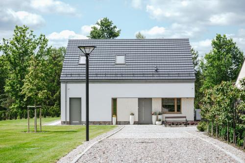a white house with a black roof at Przystań Spokoju in Chmielno
