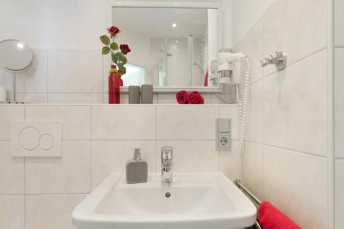 a white bathroom with a sink and a mirror at Landhaus Christophorus in Forbach