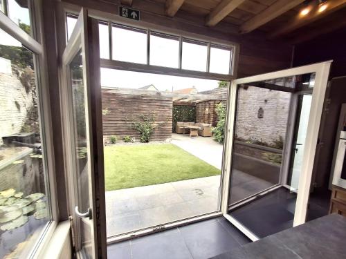 an open sliding glass door with a view of a yard at Maison Lucy In het huis van de kunstenares in Staden