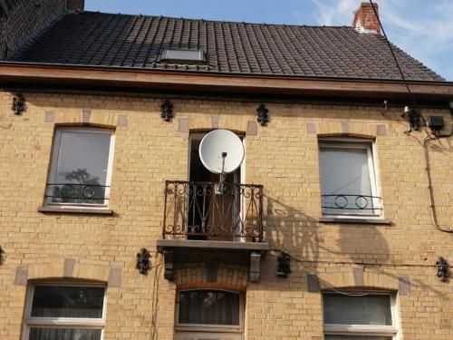 a building with a balcony with a satellite at Maison Lucy In het huis van de kunstenares in Staden