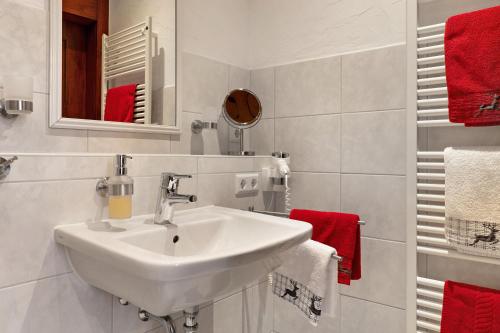 a white bathroom with a sink and red towels at Landhaus Christophorus in Forbach