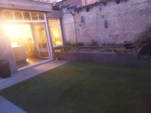 an empty patio with a lawn in front of a building at Maison Lucy In het huis van de kunstenares in Staden