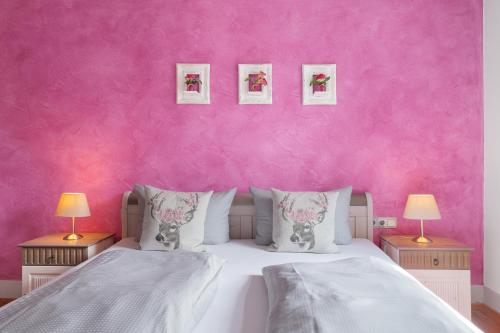 a bedroom with pink walls and a bed with pillows at Landhaus Christophorus in Forbach