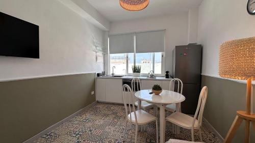 a small kitchen with a table and chairs and a refrigerator at Apartamentos Casco Antiguo in Guía de Isora