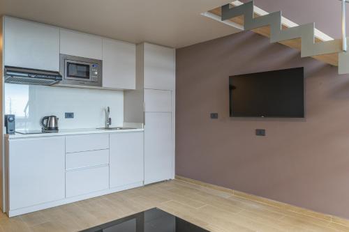 a kitchen with white cabinets and a tv on the wall at Jounieh Living - Residences by Local Host in Ed Dkârîne