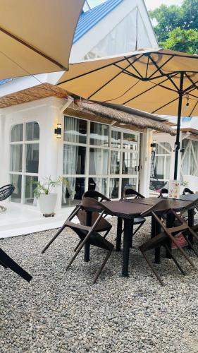 two picnic tables and umbrellas in front of a house at HayyaHayya Villas in Ocoy