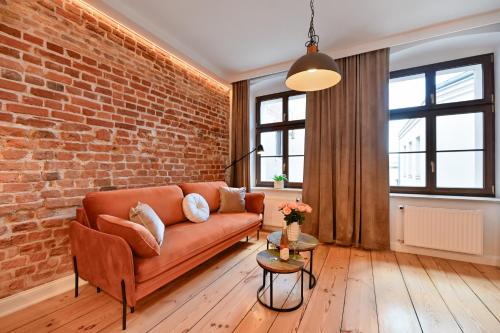 a living room with a couch and a brick wall at Szeroka Residences in Toruń