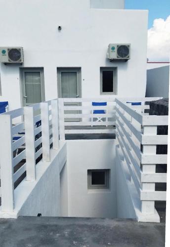 a white building with stairs and speakers on it at Fira Village Rooms in Fira