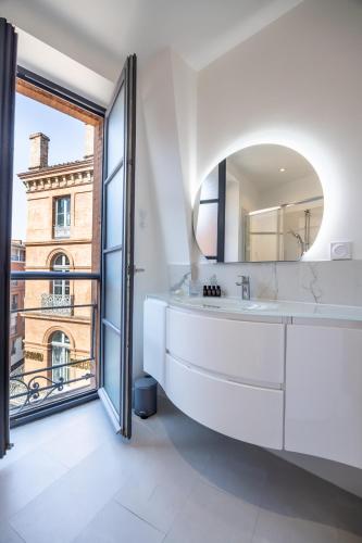 a white bathroom with a large mirror and a large window at Capitole Horizon in Toulouse