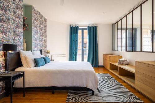 a bedroom with a large bed and blue curtains at Capitole Horizon in Toulouse