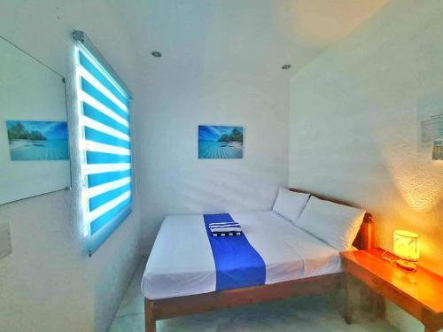 a white bedroom with a bed and a window at Jah’s Anemone Dive Guesthouse in Moalboal