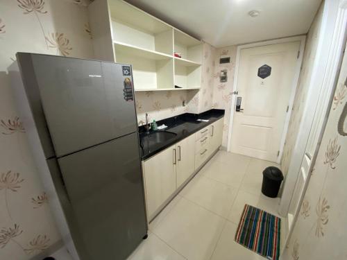 a kitchen with a stainless steel refrigerator and white cabinets at Comfy Studio Room Apartment in Semarang