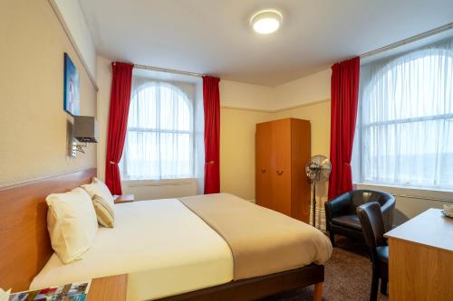 a bedroom with a bed and a desk and two windows at The Grand Scarborough in Scarborough