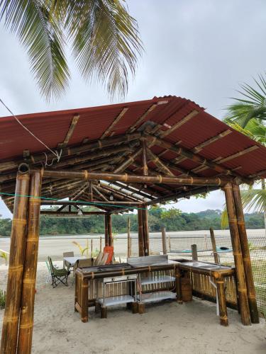 a wooden pavilion with tables and chairs on the beach at Glamping Delux! in Muisne