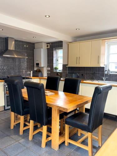 a kitchen with a wooden table and black chairs at Forgemasters House in Telford