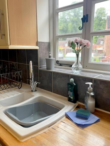 a sink in a kitchen with a vase of flowers at Forgemasters House in Telford